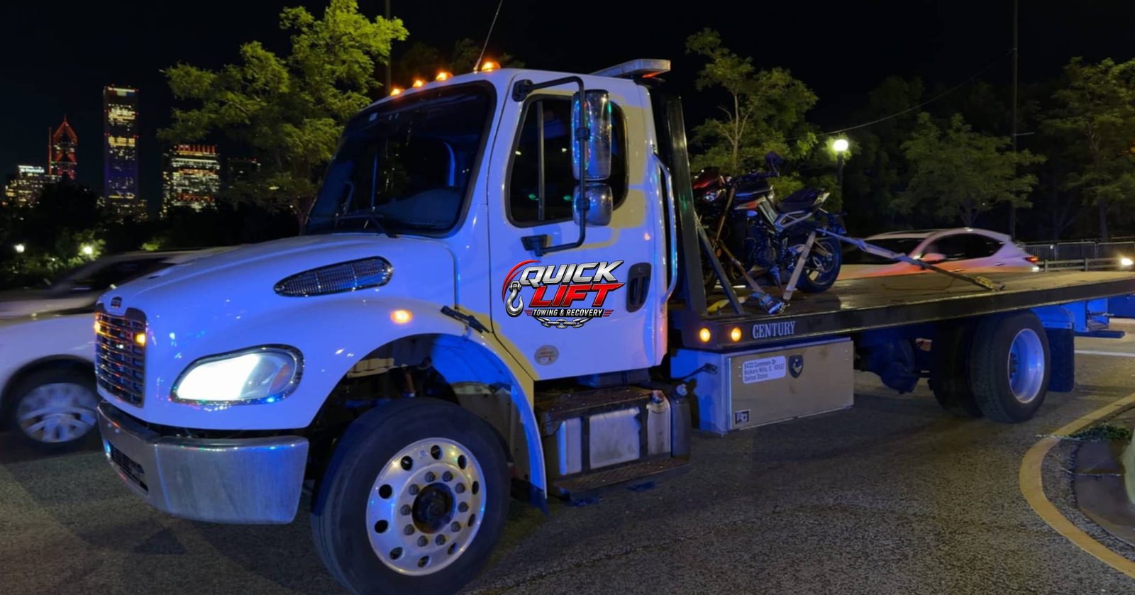Quick Lift flatbed tow truck carrying a motorcycle and car at night near Chicago
